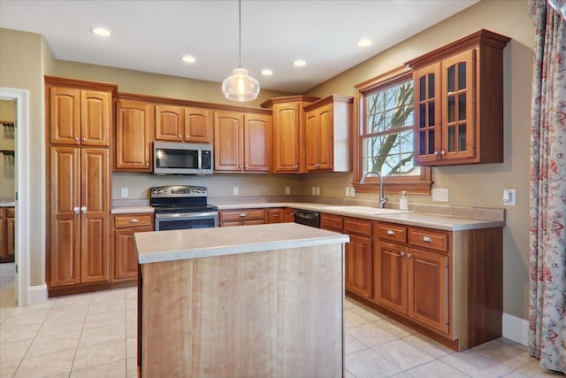 kitchen with a center island, light countertops, appliances with stainless steel finishes, glass insert cabinets, and a sink