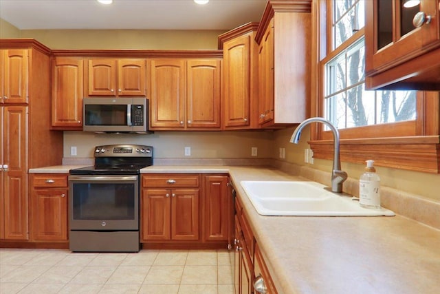 kitchen featuring brown cabinets, appliances with stainless steel finishes, light countertops, and a sink