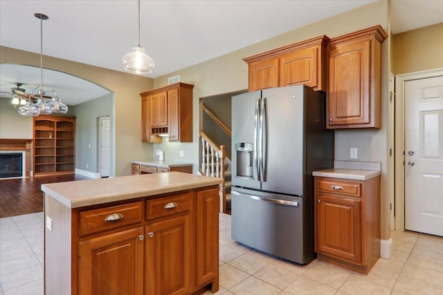 kitchen with light tile patterned floors, light countertops, brown cabinetry, and stainless steel fridge