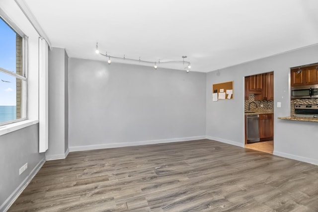 spare room with baseboards and wood finished floors