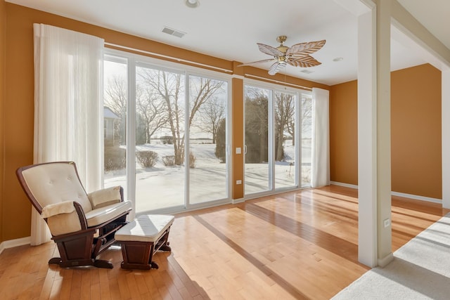 doorway to outside featuring a ceiling fan, visible vents, light wood-style flooring, and baseboards