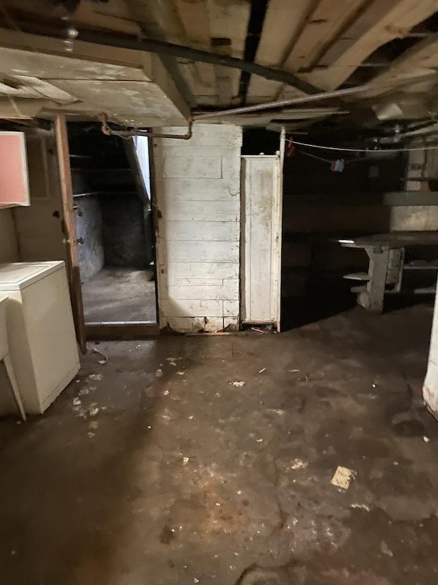 unfinished basement with washer / dryer and concrete block wall