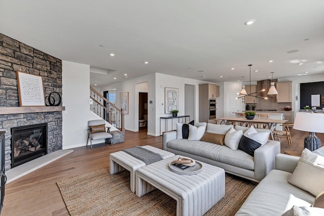 living area with recessed lighting, a fireplace, wood finished floors, baseboards, and stairs