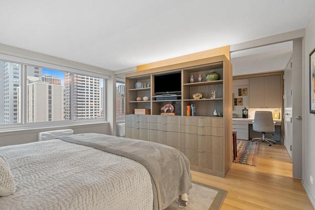 bedroom with light wood-style flooring and built in study area