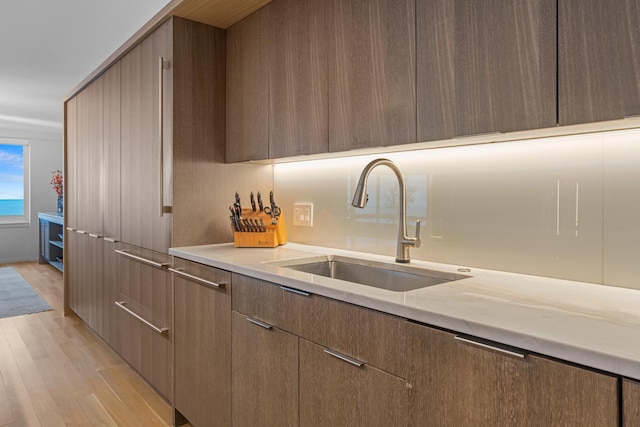 kitchen with light countertops, light wood finished floors, modern cabinets, and a sink