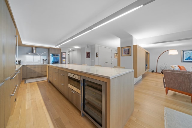 kitchen with wine cooler, a large island, stainless steel appliances, light wood-style flooring, and modern cabinets