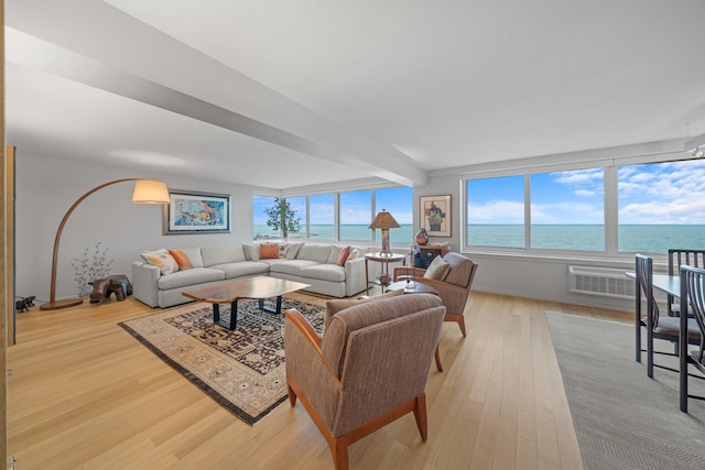 living area with light wood finished floors, a water view, and beam ceiling