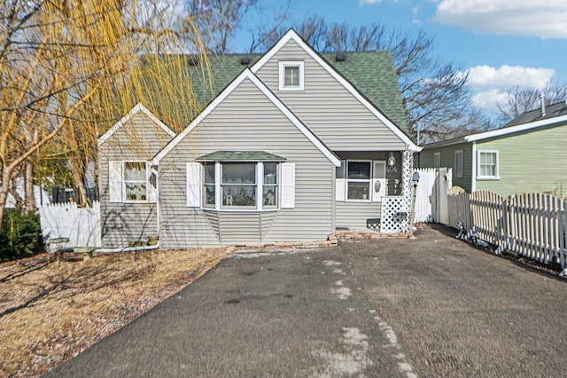 view of front of home featuring roof with shingles and fence