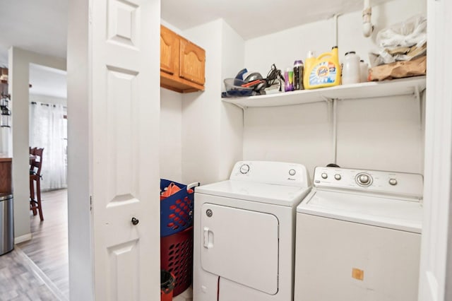 laundry area with light wood-style floors, cabinet space, and washing machine and clothes dryer