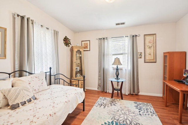 sitting room with wood finished floors, visible vents, and baseboards