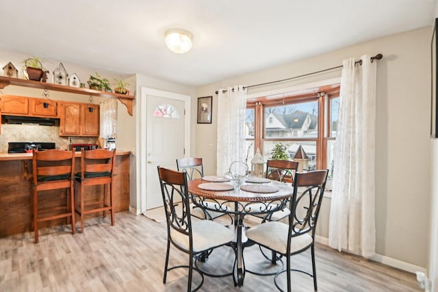 dining space featuring light wood finished floors and baseboards