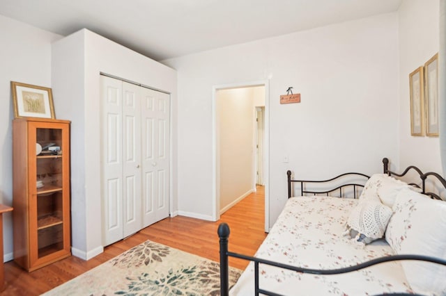 bedroom with a closet, wood finished floors, and baseboards