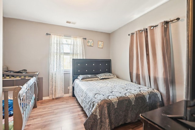 bedroom featuring wood finished floors, visible vents, and baseboards