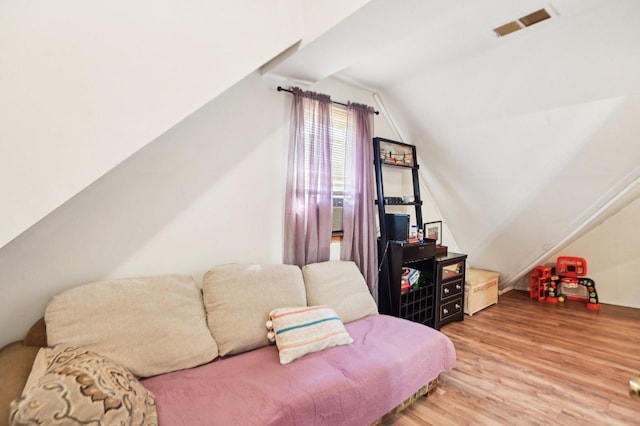 bedroom with vaulted ceiling, wood finished floors, and visible vents