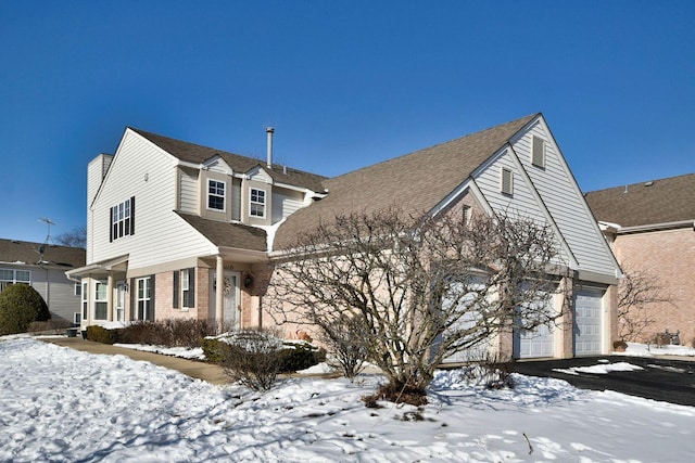 view of front of home featuring a garage, driveway, a shingled roof, and brick siding