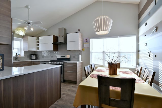 kitchen with light countertops, gas stove, white cabinets, wall chimney range hood, and modern cabinets