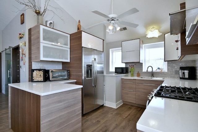 kitchen with stainless steel appliances, light countertops, glass insert cabinets, and a sink