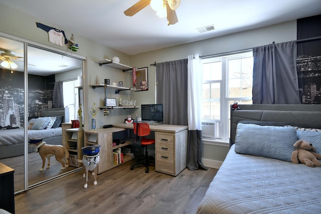 bedroom with ceiling fan, cooling unit, wood finished floors, visible vents, and a closet