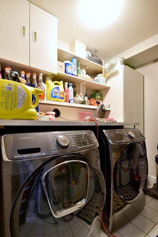 laundry area featuring separate washer and dryer, tile patterned flooring, and cabinet space