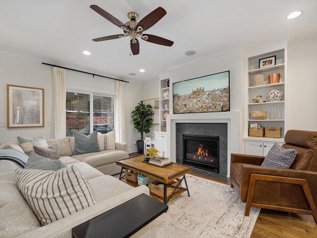 living room featuring a tile fireplace, ceiling fan, recessed lighting, and wood finished floors