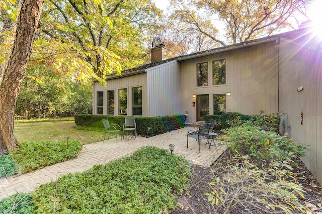 back of property with a patio, a chimney, and a lawn