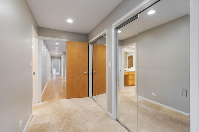 hallway featuring recessed lighting, light colored carpet, and baseboards