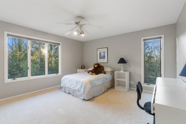 bedroom with light carpet, multiple windows, a ceiling fan, and baseboards