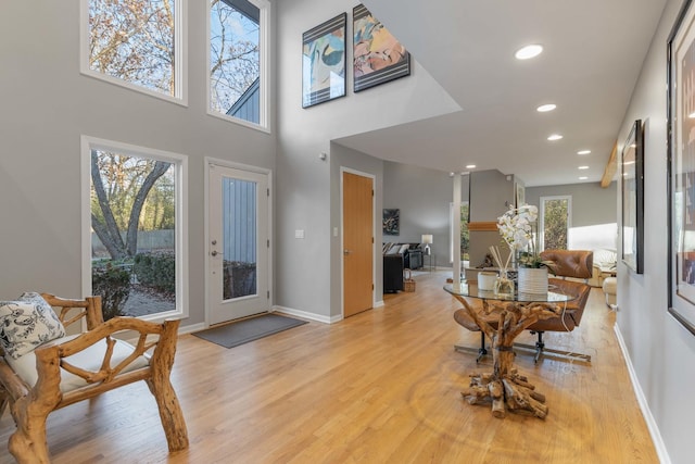 entryway featuring a towering ceiling, recessed lighting, light wood-style flooring, and baseboards