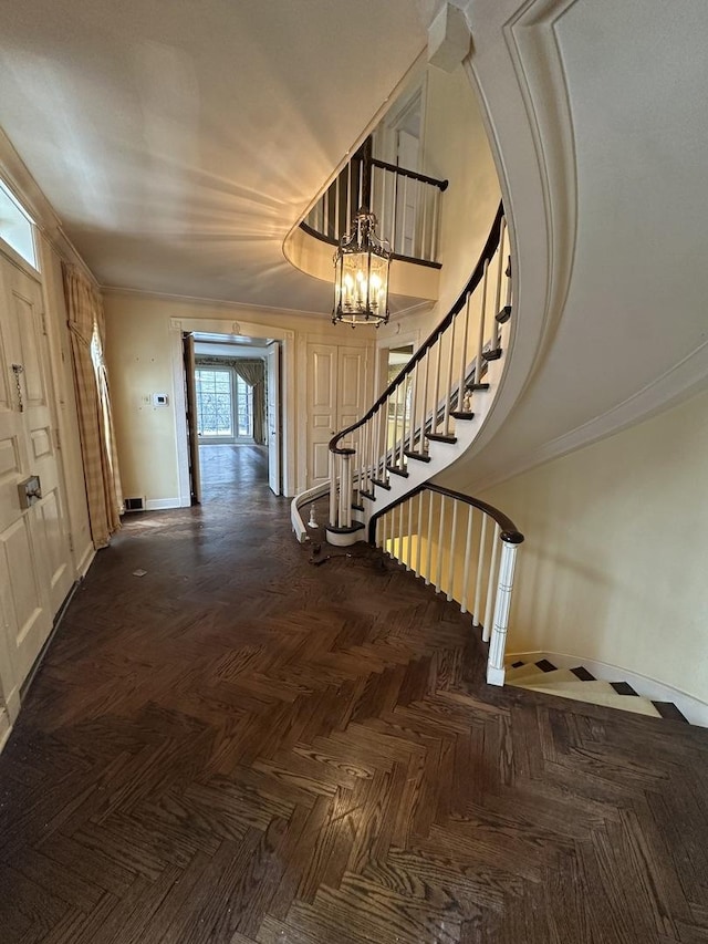 interior space with visible vents, a high ceiling, an inviting chandelier, ornamental molding, and baseboards