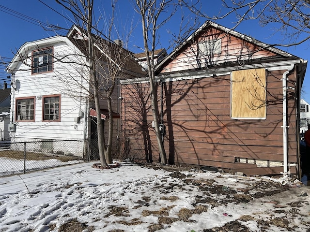 view of snow covered exterior featuring crawl space and fence