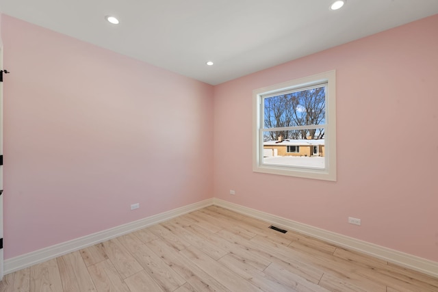 empty room featuring light wood-type flooring, visible vents, baseboards, and recessed lighting