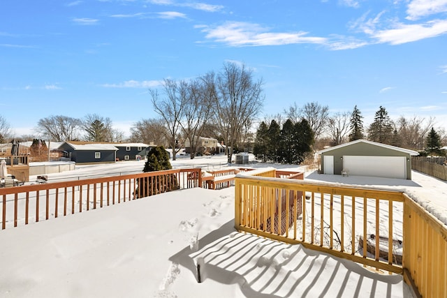 snow covered deck with a garage, an outdoor structure, and a residential view