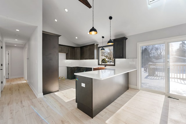 kitchen featuring a peninsula, a sink, light countertops, light wood finished floors, and pendant lighting