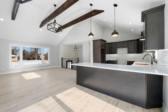 kitchen with hanging light fixtures, a sink, light countertops, light wood-style floors, and beam ceiling