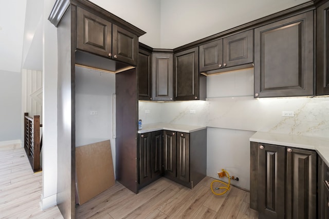 kitchen featuring light countertops, dark brown cabinets, backsplash, and light wood-style floors