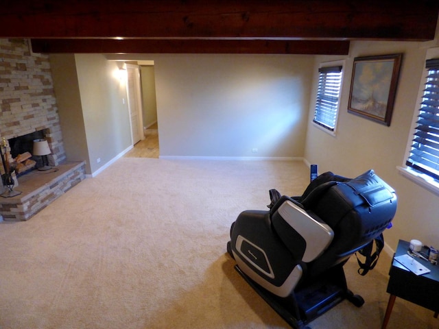 living area with carpet, beam ceiling, a stone fireplace, and baseboards