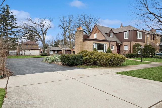 view of front of house featuring a front yard, brick siding, and a chimney