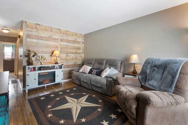 living area featuring dark wood-type flooring and a glass covered fireplace