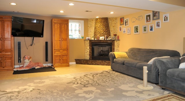 living area featuring baseboards, visible vents, a fireplace with raised hearth, and recessed lighting