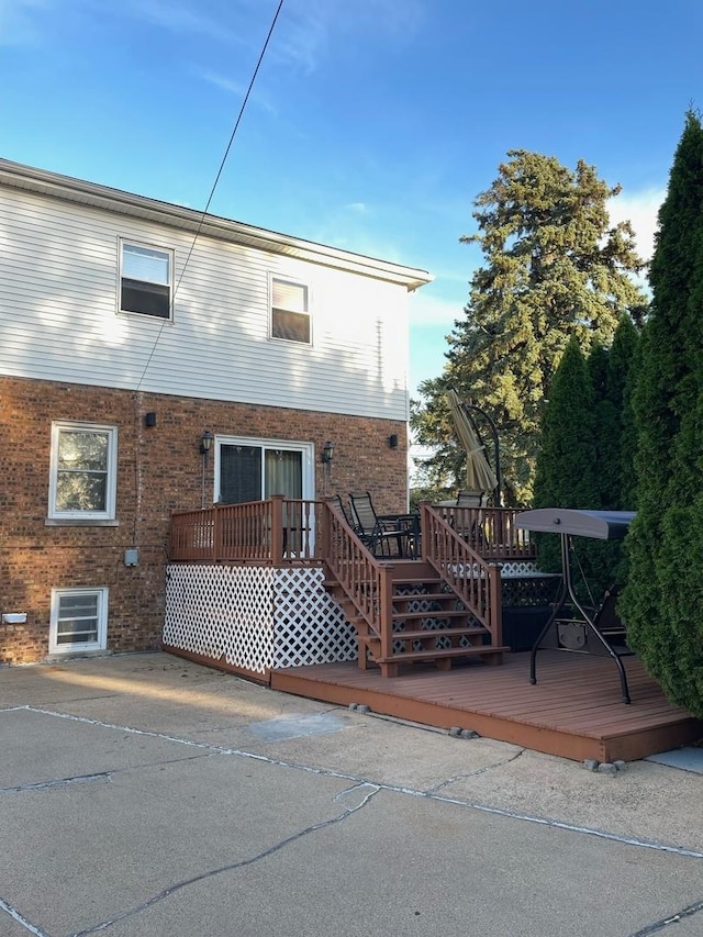 back of property featuring brick siding and a wooden deck