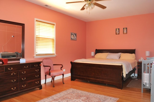 bedroom featuring light wood finished floors, visible vents, baseboards, and a ceiling fan