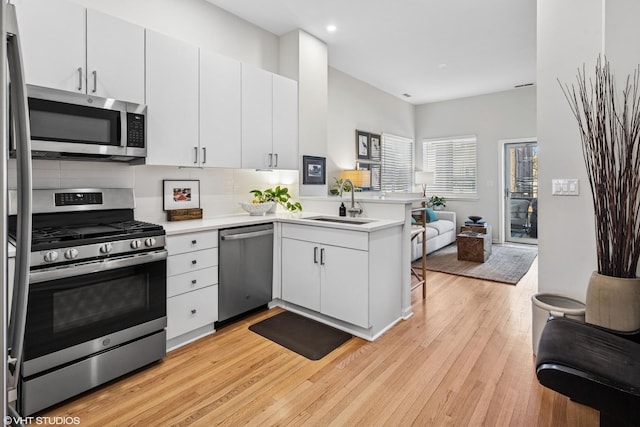 kitchen with a peninsula, white cabinetry, appliances with stainless steel finishes, and light countertops