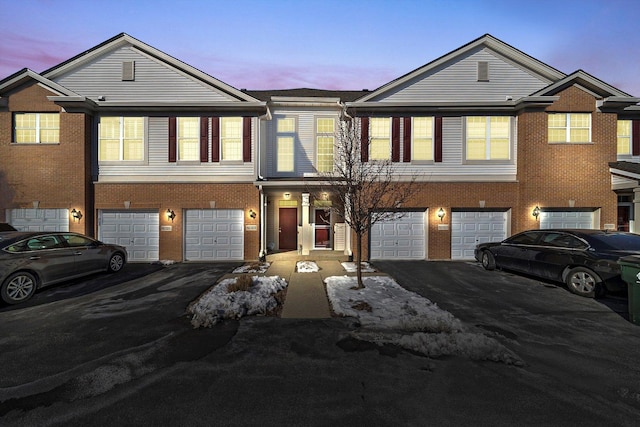 view of property featuring a garage, driveway, and brick siding