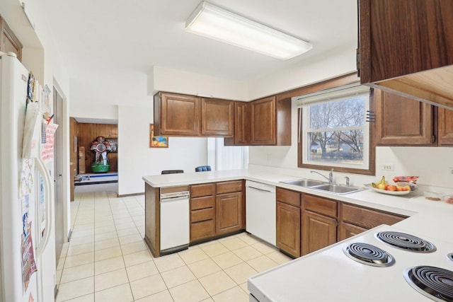 kitchen with white appliances, a sink, a peninsula, and light tile patterned floors