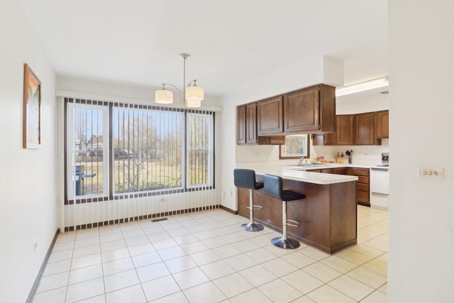 kitchen with a notable chandelier, a peninsula, white electric range, visible vents, and light countertops