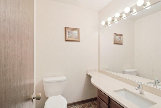 bathroom with baseboards, vanity, and toilet