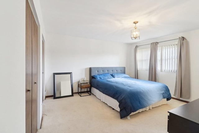 bedroom featuring light carpet, baseboards, and a chandelier