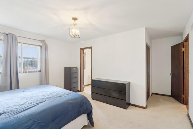 bedroom featuring light carpet, ensuite bathroom, baseboards, and an inviting chandelier