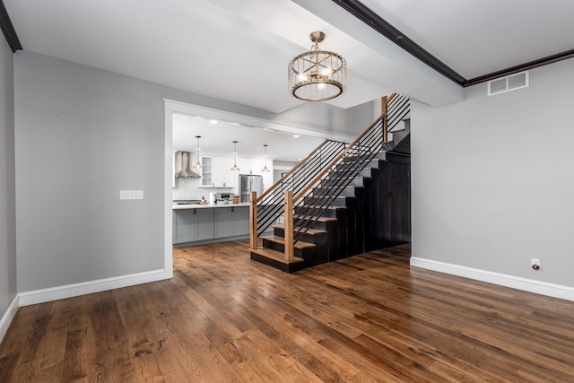 unfurnished living room featuring baseboards, stairway, visible vents, and an inviting chandelier