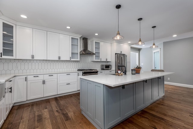 kitchen with glass insert cabinets, light countertops, appliances with stainless steel finishes, and wall chimney exhaust hood